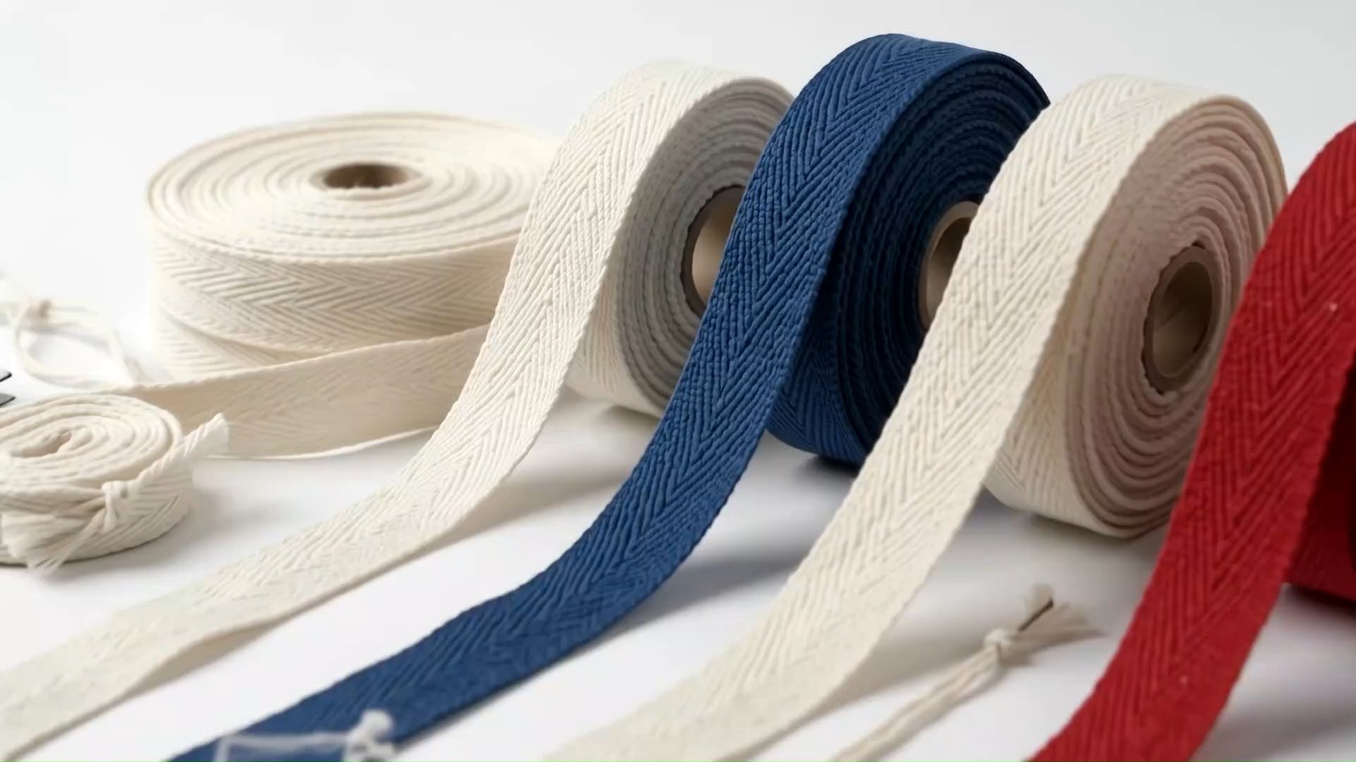 Woven textile tape emerging from loom mechanisms during production